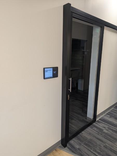 The Town Hall display tablet mounted on the wall outside the room at Granite City Workspaces